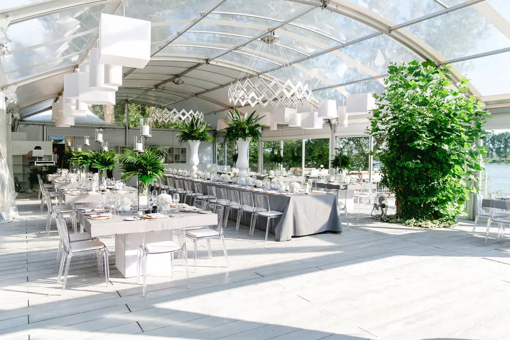 Helle Hochzeitstafeln mit Greenery im transparenten Zelt