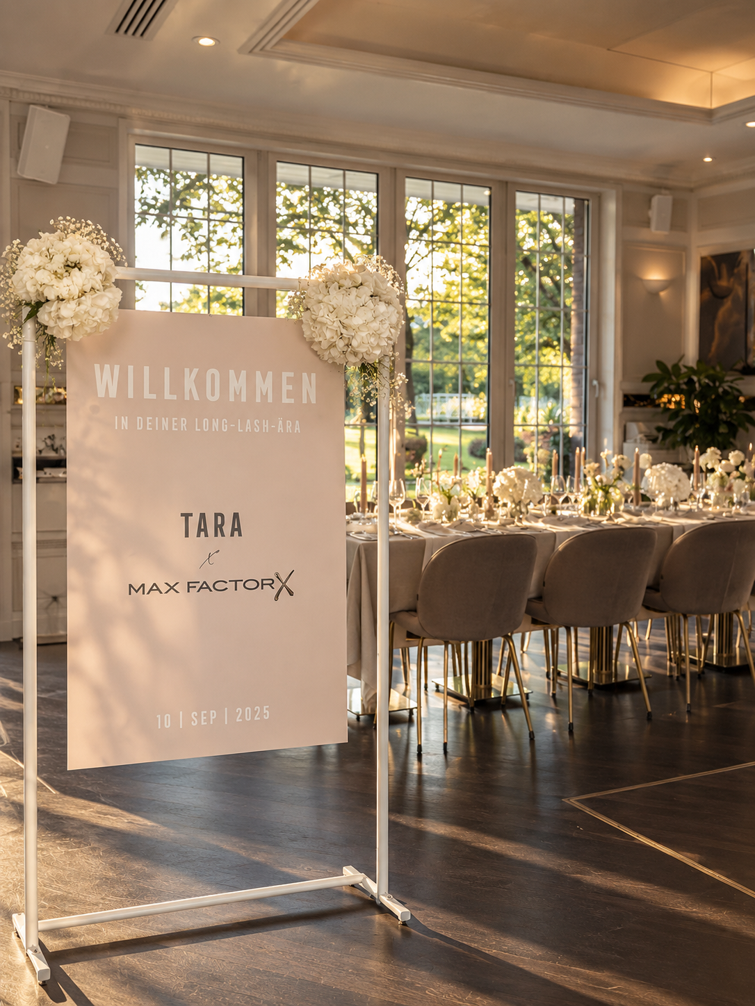 Willkommensschild für Tara × Max Factor vor einer festlich gedeckten Tafel im warmen Abendlicht