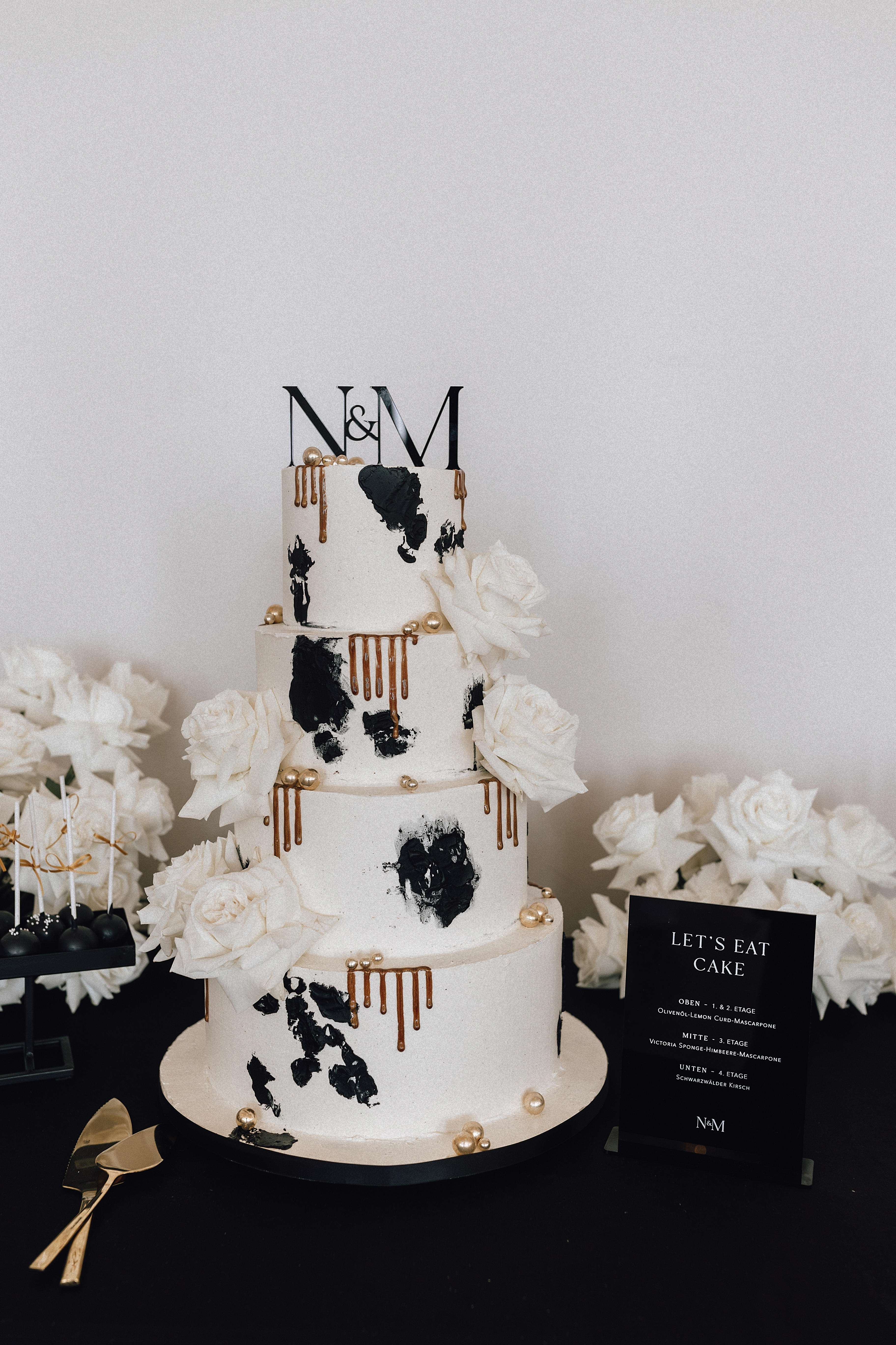 Hochzeitstorte mit N&M-Topper und schwarzem Tortenschild
